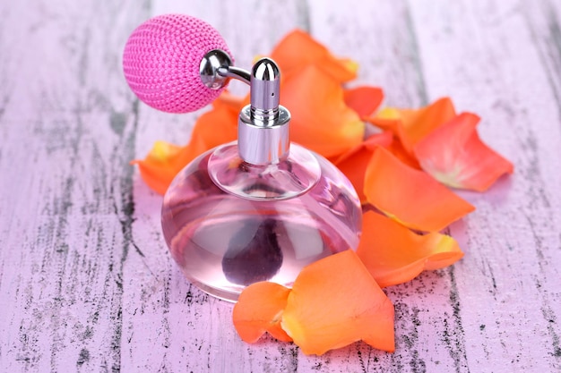 Perfume bottle with petals on table closeup