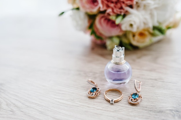 Perfume earring and ring lying on a bouquet of flowers background Bride accessories Close up Side view