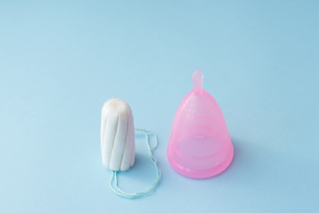 Period products tampon and menstrual cup on blue background