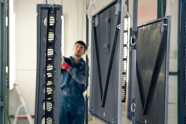 Perm, Russia - September 21, 2022: worker moves metal parts to a powder coating booth