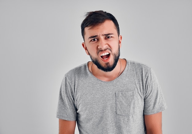 Perplexed indignant hipster has dark stubble, gestures with puzzlement, being discontent with recent news, has to change job position,