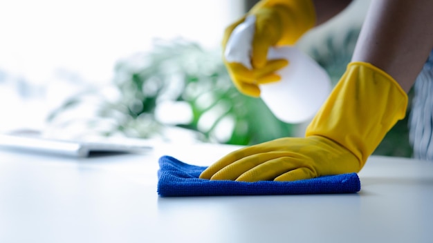 Person cleaning the room cleaning staff is using cloth and spraying disinfectant to wipe the tables in the company office room Cleaning staff Maintaining cleanliness in the organization