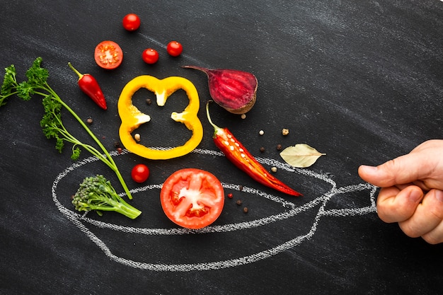 Person cooking veggies on chalk pan 