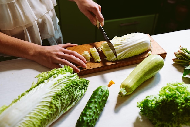 A person cuts a cabbage on a cutting board.