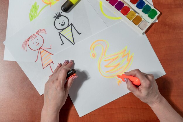 Photo a person drawing a swan with a yellow marker on a table.