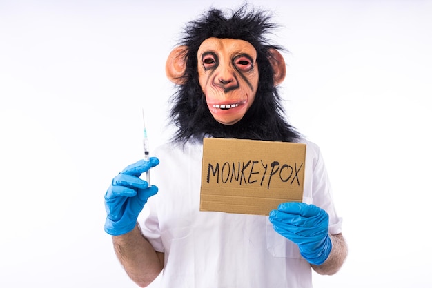 Person dressed in a monkey with a mask with a medical nurse39s suit with a sign that reads 39MONKEYPOX39 and a syringe on a white background Pandemic virus epidemic Nigeria and smallpox concept