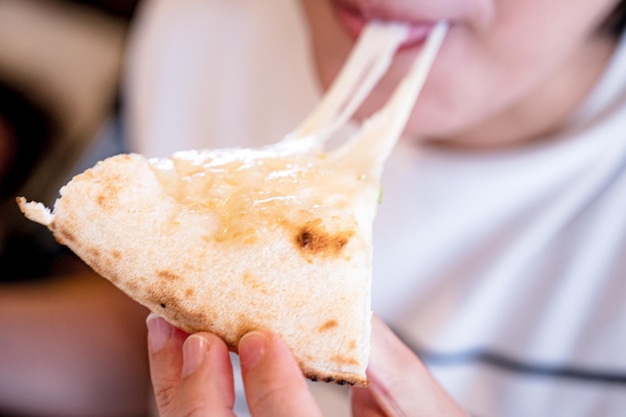 A person eating a slice of cheese pizza