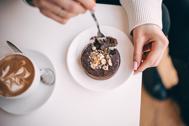 Photo a person enjoying a delicious chocolate dessert with coffee in a cozy cafe setting on a sunny day