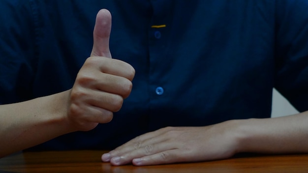 A person giving a thumbs up in front of a table