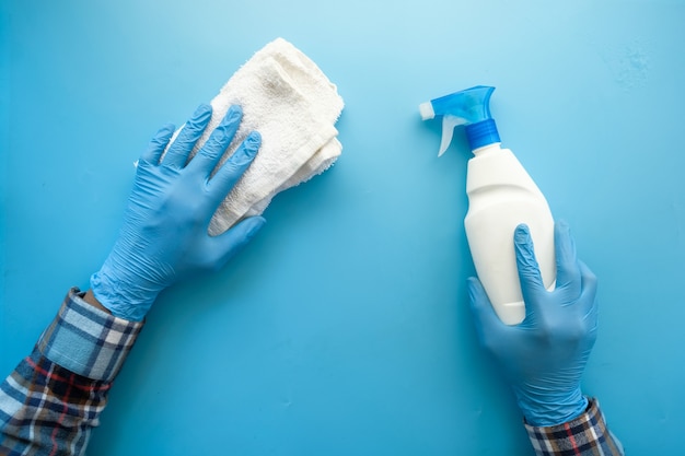 Person hand in disposable gloves using disinfectant spray to clean table surface 