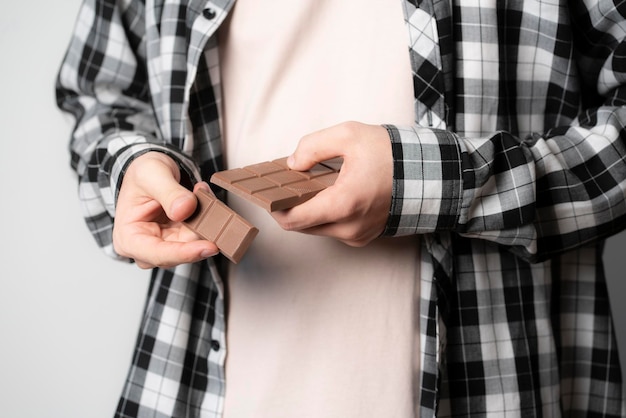 A person holding and braking black chocolate bar