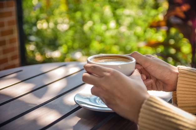 Photo person holding cup of coffee on wooden table