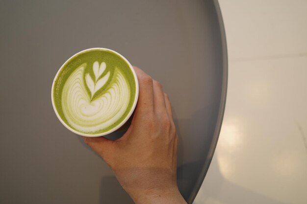 a person holding a cup of latte art with a design on it