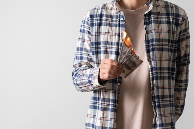 A person holding a dollar banknote and burning it with fire