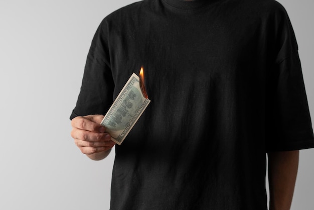 A person holding a dollar banknote and burning it with fire