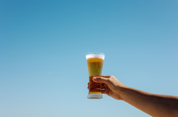 The person holding a glass of beer against the background of the sea