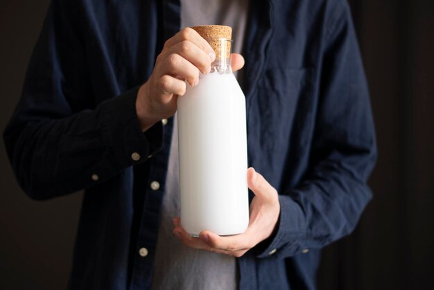 A person holding glass bottle with vegan milk