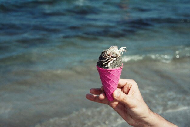 Photo person holding ice cream cone at beach