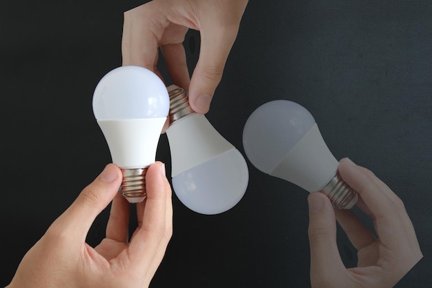 A person holding a light bulb that is being held by two hands.