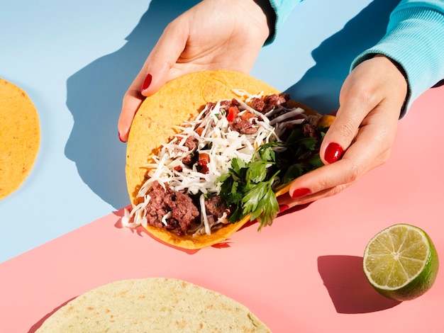 Person holding a mexican taco in hands high view