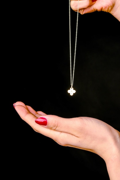 a person holding a necklace with a cross on it