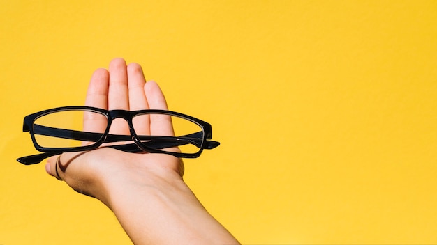 Person holding a pair of eyeglasses with copyspace