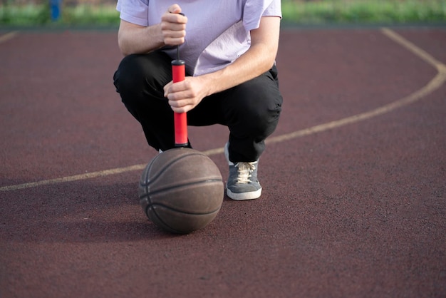 A person holding a red hand pump and basketball ball