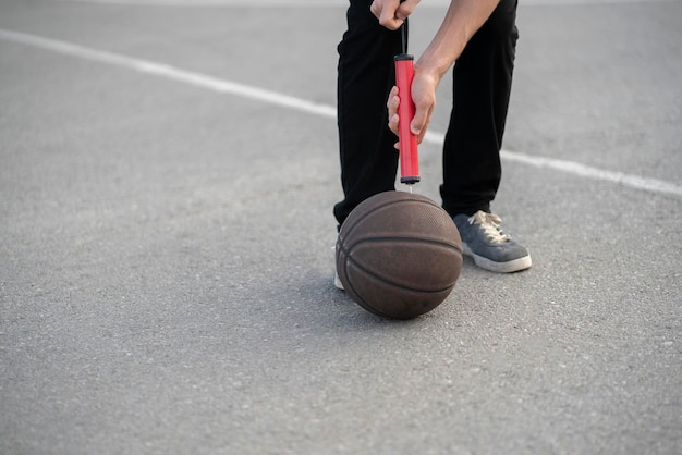 A person holding a red hand pump and basketball ball