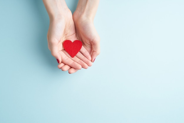 A person holding red heart in hands