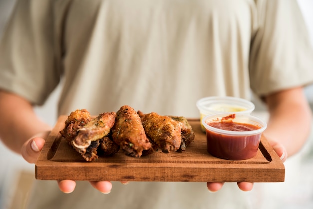 Photo person holding serving board with spicy wings