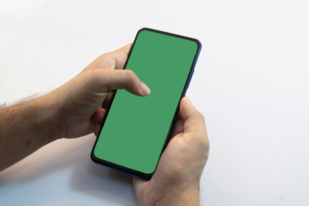 Person holding a smartphone with green screen