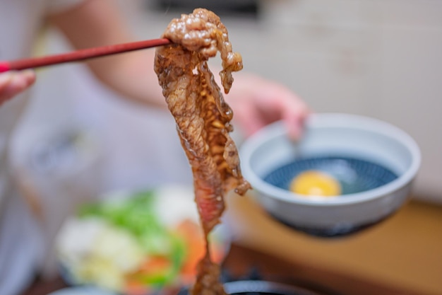 A person holding a stick with a bowl of food in the background