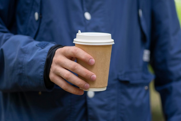 A person holding take away paper cup with hot drink