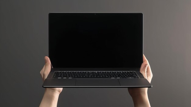 A person holds a laptop with the screen open.