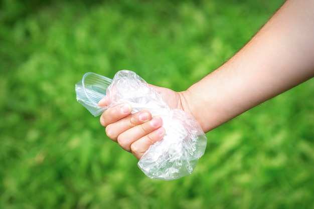 The person holds used crumpled plastic debris in his hand. Environmental problem concept.