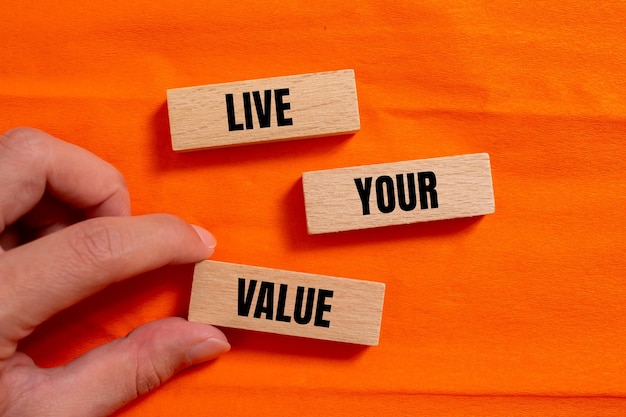 Photo a person holds a wooden block with the words live your value