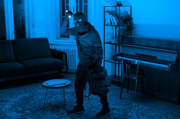 Person in hoodie exploring a bluelit room