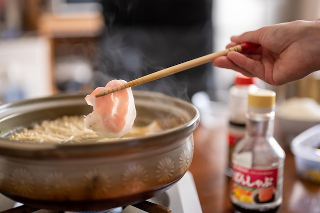 A person is cooking a chicken noodle with a stick