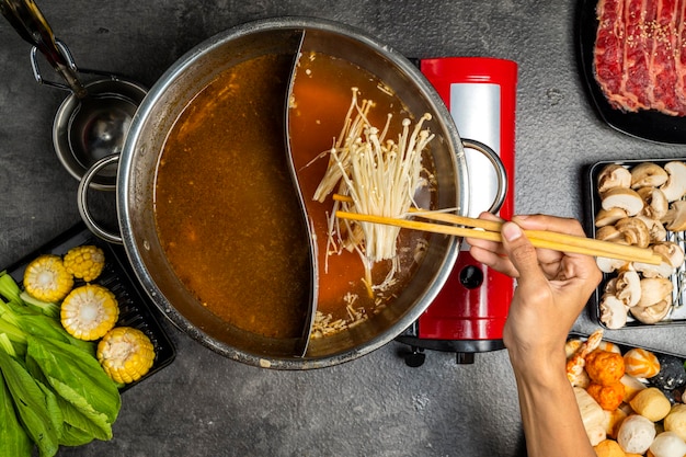 Photo a person is cooking a dish with two bowls of soup and a red pot