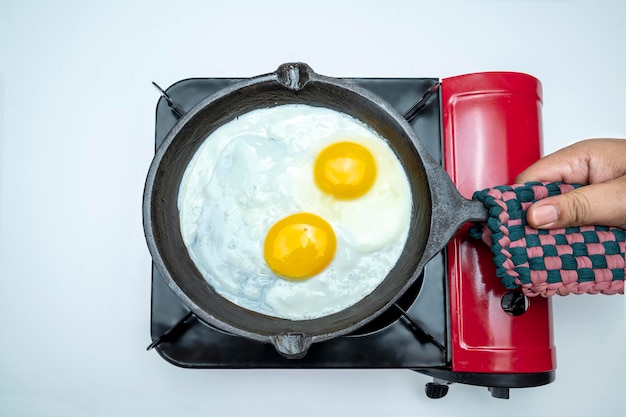 A person is cooking eggs in a pan on a stove