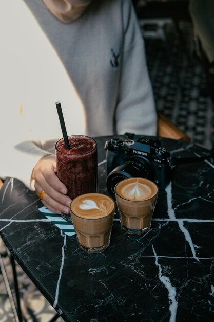 A person is holding a cup of coffee and a camera next to it