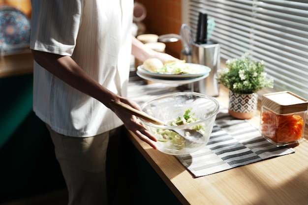 A person is preparing food in a kitchen with a potted plant on the table.