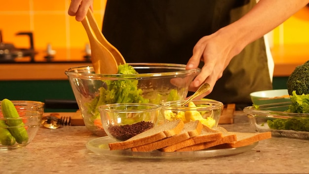 A person is putting a salad in a bowl