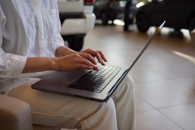 A person is seen typing on a laptop in a modern office setting with cars in the background