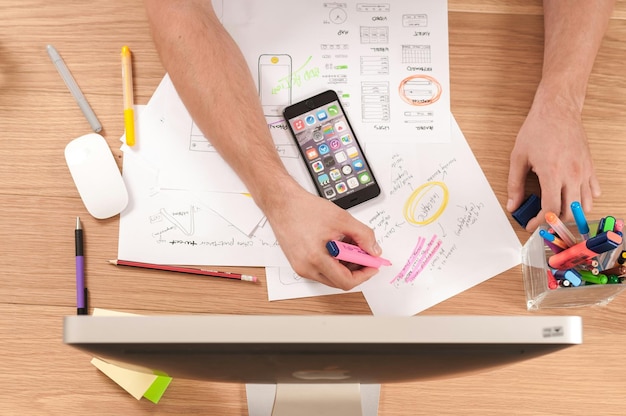 a person is using a cell phone on a desk with a piece of paper with a pen and pencil