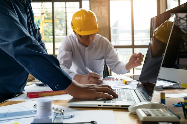 a person is using a computer and explaining the building construction to others in the background