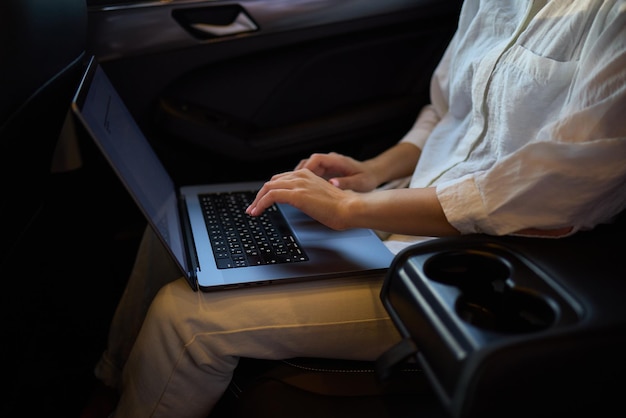 Photo a person is working on a laptop inside a car during their commute to a destination