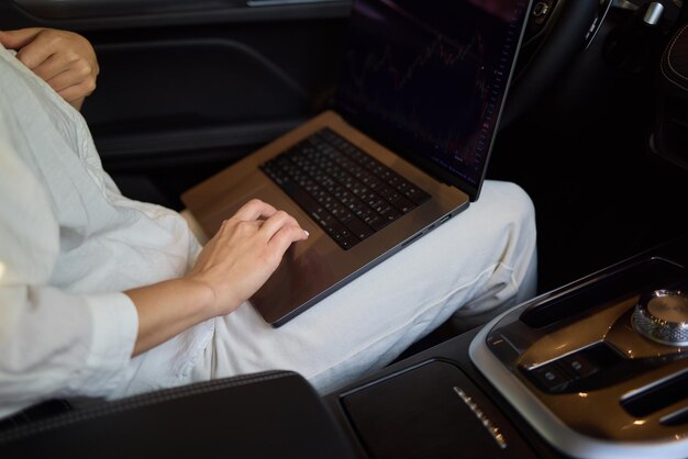 A person is working on a laptop inside a car during their commute to a destination