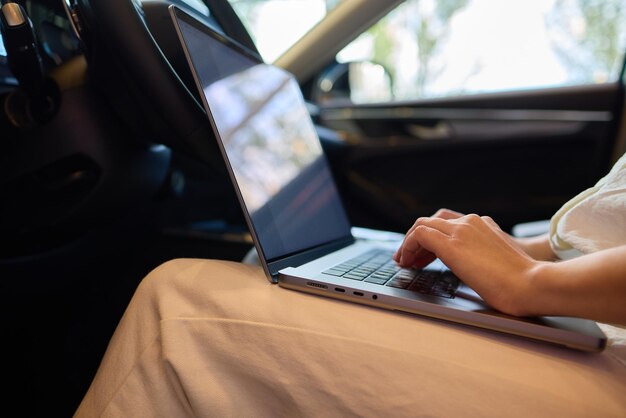 A person is working on a laptop inside a car during their commute to a destination