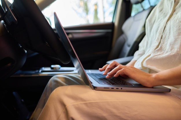 A person is working on a laptop inside a car during their commute to a destination